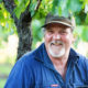 Grower Mark Lucas sitting amongst vines smiling with cap on